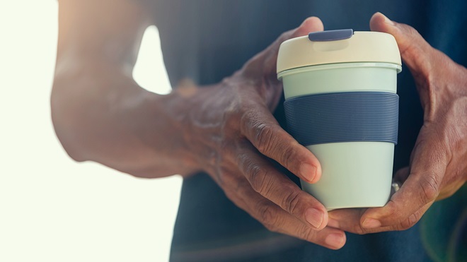 closeup of person holding a reusable coffee cup
